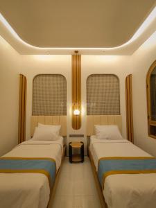 two beds in a room with two windows at Hotel Besar Purwokerto in Purwokerto