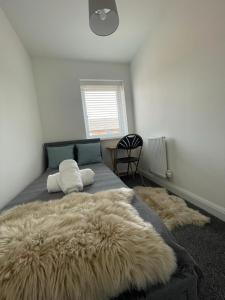 a bedroom with a large bed with a furry rug on it at Barry Waterfront Stays - ENTIRE 3 BED PROPERTY in Barry