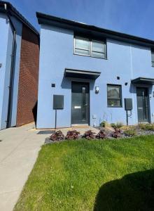 een blauw huis met ramen en een grasveld bij Barry Waterfront Stays - ENTIRE 3 BED PROPERTY in Barry