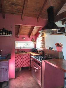 a kitchen with pink walls and a stove top oven at Cabaña Los Ulmos Bariloche in San Carlos de Bariloche