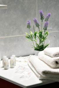 un mostrador de baño con toallas y un jarrón con flores púrpuras en Affitti turistici: OASI FELICE, en Torrile