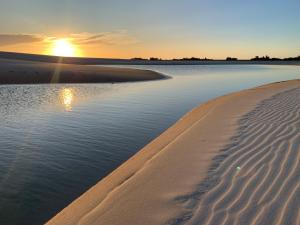 a beach with the sun setting over the water at Vila das Águas in Atins +79 photos