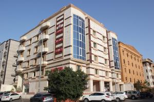 Altamyoiz Sirved Apartments في جدة: مبنى طويل وبه سيارات متوقفة أمامه
