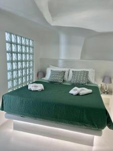 a bedroom with a green bed with two towels on it at Aidos Villa Santorini in Megalochori