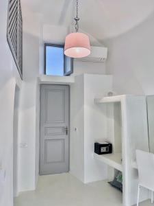 a hallway with a white door and a pink lamp at Aidos Villa Santorini in Megalokhori