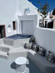 a white patio with a bench and a swimming pool at Aidos Villa Santorini in Megalochori