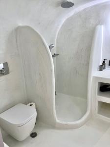 a white bathroom with a toilet and a bath tub at Aidos Villa Santorini in Megalokhori