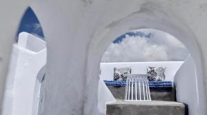 a white building with a table and zebras at Aidos Villa Santorini in Megalokhori