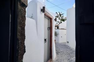a narrow alley with white walls and a door at Aidos Villa Santorini in Megalokhori