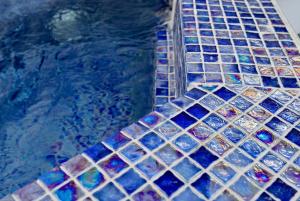 a swimming pool with blue and purple glass tiles at Aidos Villa Santorini in Megalokhori