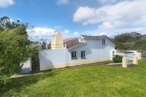 a white house with a grass yard at Casa da Batalha in Ponta Delgada