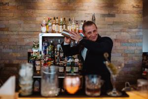 Um homem atrás de um bar a misturar bebidas. em Astoria Resort em Riva del Garda