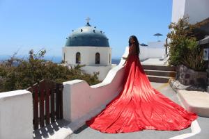 a woman in a red dress walking down a staircase at Aidos Villa Santorini in Megalokhori