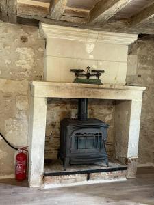 a stone fireplace with a stove in a room at Gite des vieilles pierres in Seigy