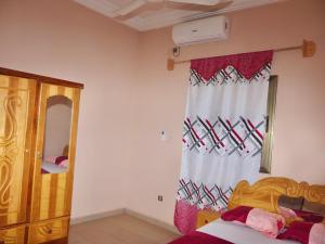 1 dormitorio con cama y ventana con cortina en Appartement et Chambres en Bamako