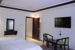 a bedroom with two beds and a television on the wall at Altamyoiz Sirved Apartments in Jeddah