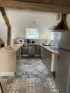 a kitchen with stainless steel appliances and a tile floor at Gite des vieilles pierres in Seigy