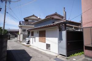 una casa blanca con un garaje en una calle en パライソ梅田 en Ise