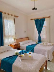 a hotel room with two beds with blue curtains at Hotel Sema in Patara