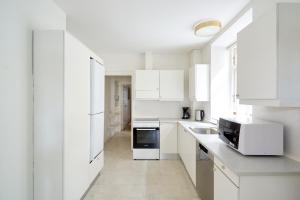 a white kitchen with white cabinets and a sink at Famous Lakes Apt - City Central in Copenhagen