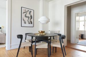 uma sala de jantar com uma mesa preta e cadeiras em Famous Lakes Apt - City Central em Copenhague