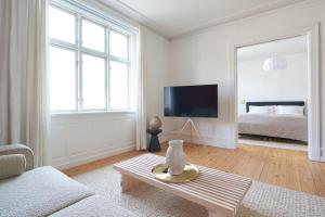 uma sala de estar com um sofá, uma televisão e uma cama em Famous Lakes Apt - City Central em Copenhague