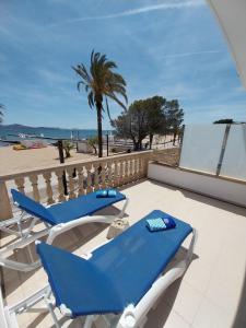 un par de sillones azules en un patio con la playa en Apartamentos Torre Playa en Puerto Pollensa