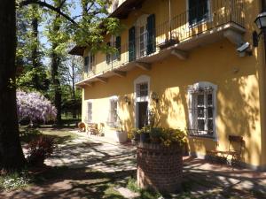 - un bâtiment jaune avec une terrasse couverte et un balcon dans l'établissement Villa Mirano Bed & Breakfast, à Piossasco