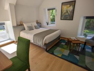 1 dormitorio con 1 cama y 1 silla verde en Le Clos du Val, en Quibou