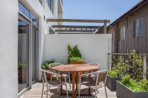 a patio with a wooden table and chairs at Edgy On Bree in Cape Town