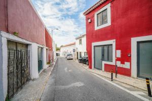 an empty street with red and white buildings and a car at Alvito Charm Apartments in Lisbon