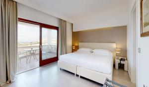 a bedroom with a white bed and a balcony at Hotel Monte Sarago in Ostuni