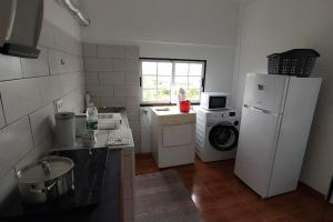 a kitchen with a refrigerator and a washer and dryer at Casa dos Fenais in Praia da Graciosa