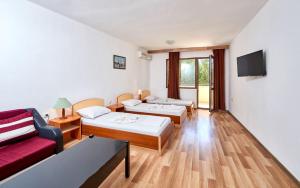 プリモルスコにあるHotel Koralのベッド2台と赤いソファが備わるホテルルームです。