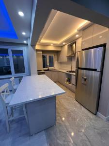 Il comprend une cuisine équipée d'un réfrigérateur en acier inoxydable et d'une table. dans l'établissement SÜPER KONUMDA LUX,ŞÖMİNELİ TASARIM DAİRE, à Istanbul