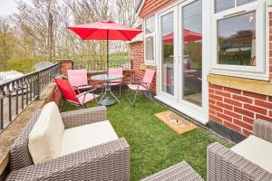 Bedlington的住宿－Host & Stay - The Paddock，庭院配有椅子和桌子及遮阳伞
