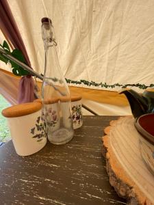 a bottle on a table next to two cups at Hollington Park Glamping in Newbury