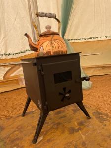a black stove with a tea kettle on top at Hollington Park Glamping in Newbury