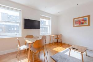 um quarto com uma mesa e cadeiras e uma televisão de ecrã plano em Contemporary 1BD Flat - Camden em Londres