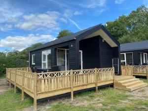 een zwart huis met een houten hek en een veranda bij Rosenvold Strand Camping in Stouby