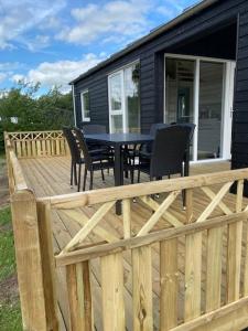a wooden deck with chairs and a table on a house at Rosenvold Strand Camping in Stouby