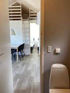 a bathroom with a toilet and a dining room with a table at Rosenvold Strand Camping in Stouby