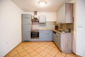 a kitchen with white appliances and a tile floor at Apartment Rimljanček in Leskovec pri Krškem