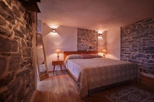 - une chambre avec un lit et un mur en pierre dans l'établissement "La Casa dei Gelsi" - Panorama Lodge MONTE GENEROSO, à Scudellate