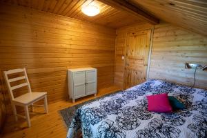 1 dormitorio con 1 cama y 1 silla en una cabaña en Villa Jukanranta, Sorjosen lomamökit, en Sulkava