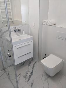 a white bathroom with a toilet and a sink at LUXURY AQUA APARTMENTS przy AQUAPARK REDA in Rumia