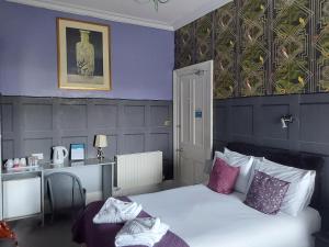 Un dormitorio con una cama con paredes moradas y una mesa. en East Claremont Guest House, en Edimburgo
