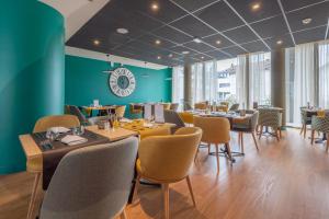 a restaurant with tables and chairs and a green wall at DOMITYS L'HOROLOGIA in Cluses