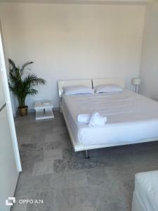- une chambre avec un lit blanc et une plante en pot dans l'établissement Résidence Le Persepolis 50 m de la mer, à Cagnes-sur-Mer