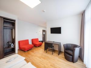 ein Wohnzimmer mit 2 Stühlen, einem Tisch und einem TV in der Unterkunft sevenDays Hotel BoardingHouse in Heidelberg